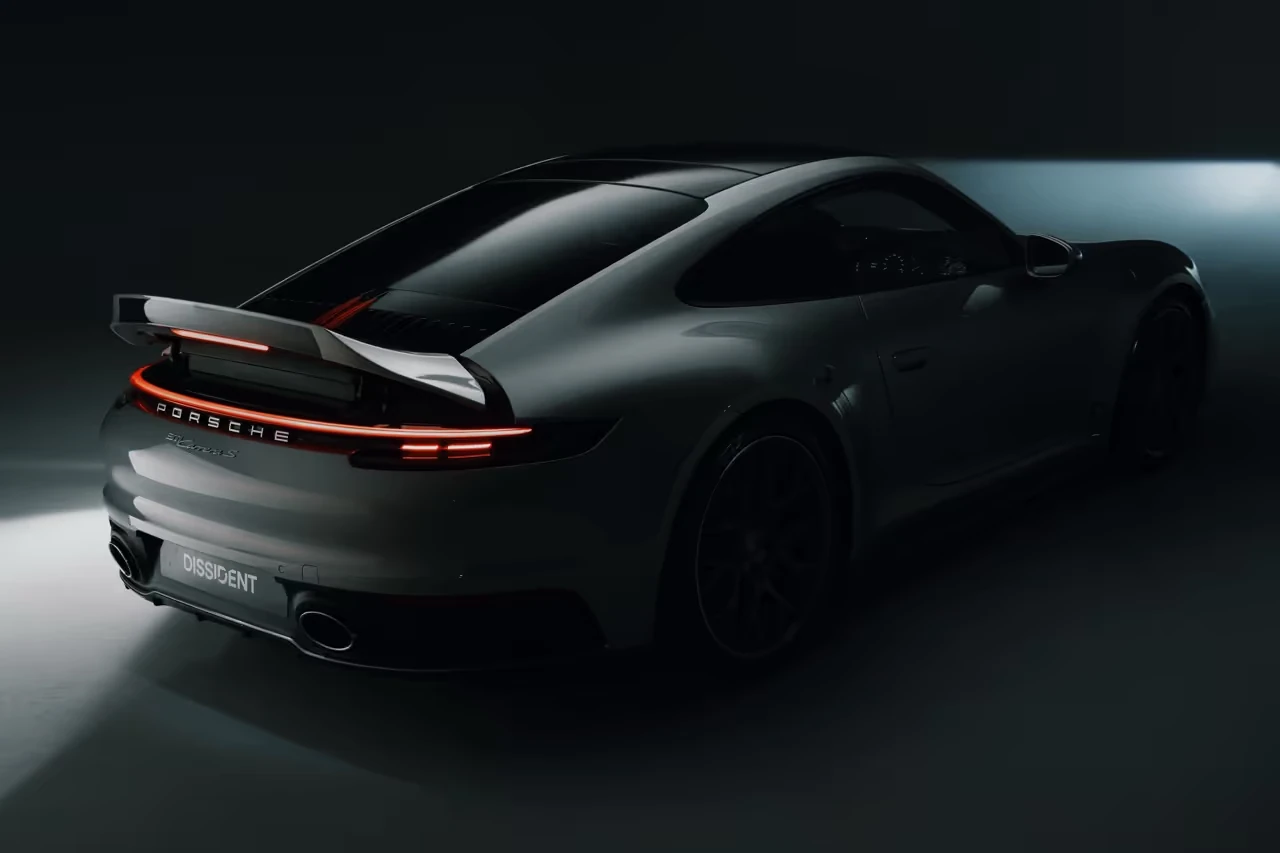 A dark Dissident Porsche 911 with a sculpted ducktail and illuminated rear lights