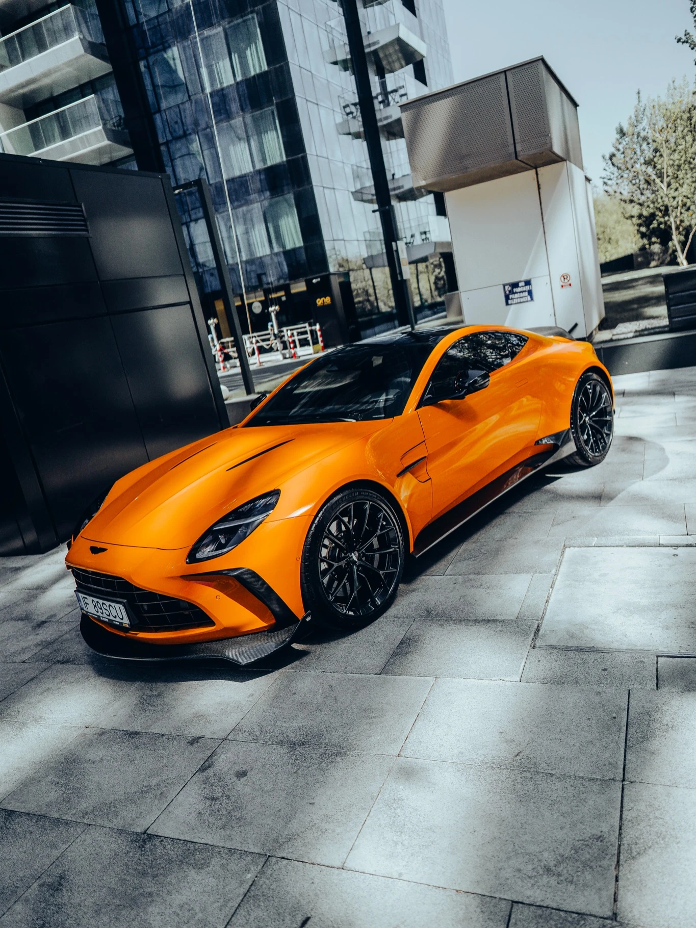 Orange OLIGARCH Aston Martin Vantage outside a glass-fronted building