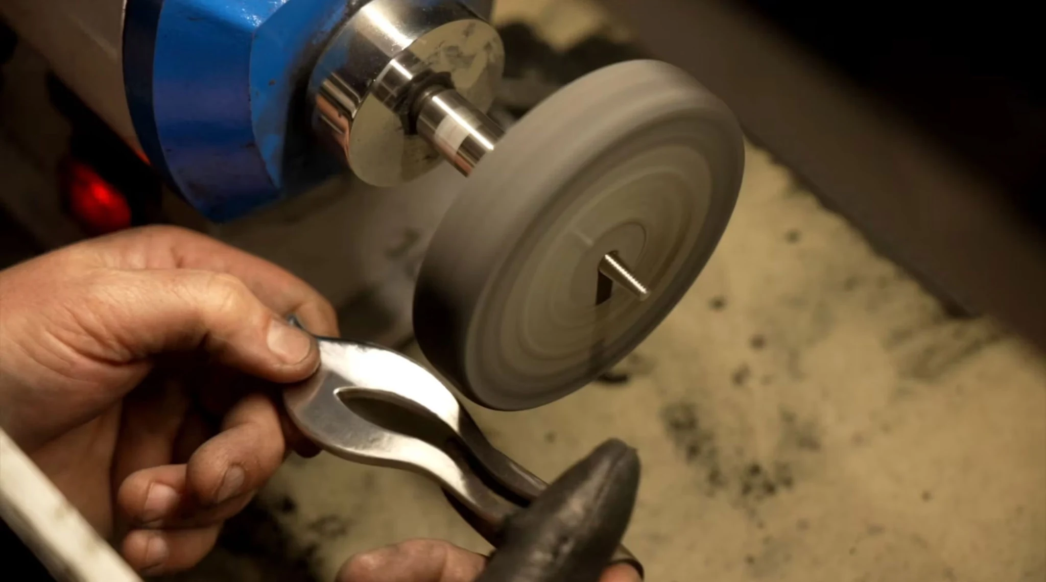 A craftsperson finishing a metal component by hand